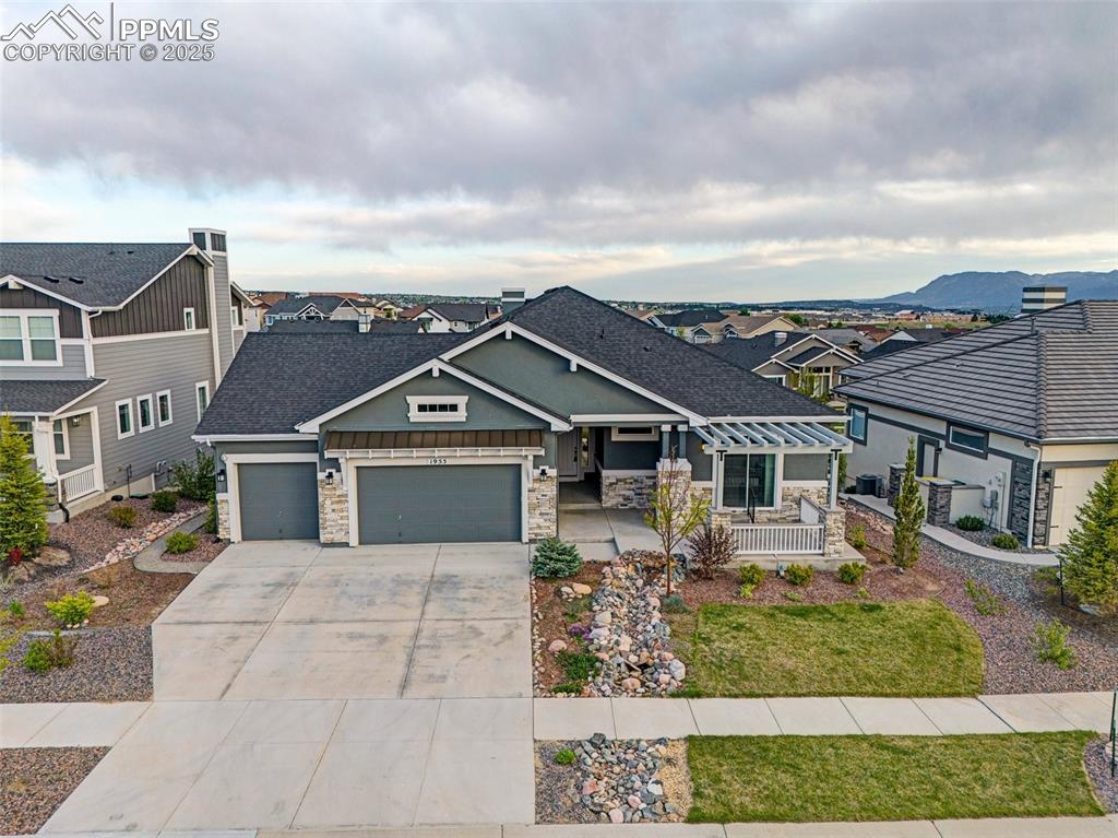 View of front of property with a garage, stone siding, and roof with shingles