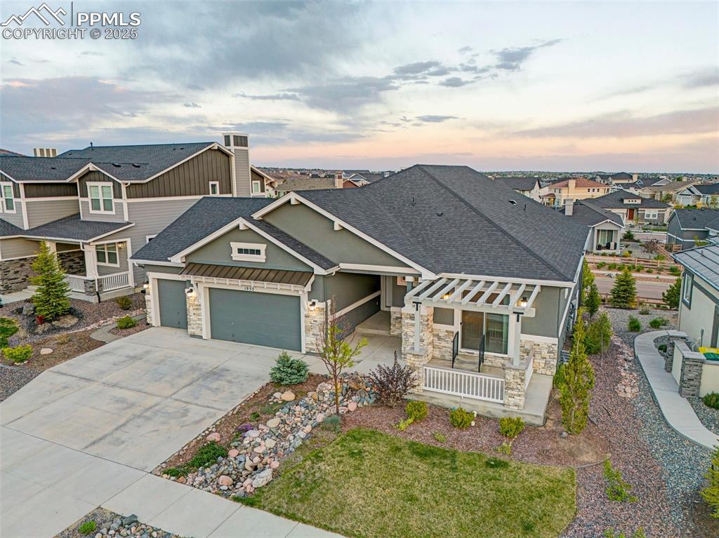 Craftsman-style home with stone siding, roof with shingles, a garage, and concrete driveway