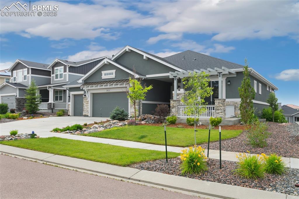 Craftsman inspired home with stone siding, a front lawn, driveway, and a porch