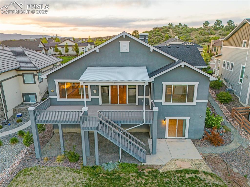 Back of house at dusk with stucco siding, a patio, stairs, a wooden deck, and metal roof