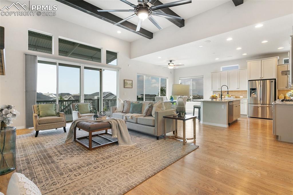 Living room featuring ceiling fan, beam ceiling, light wood-type flooring, and recessed lighting