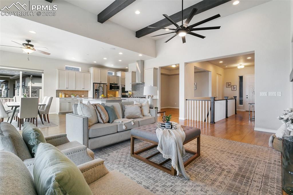 Living room with a ceiling fan, recessed lighting, light wood-style floors, and beamed ceiling