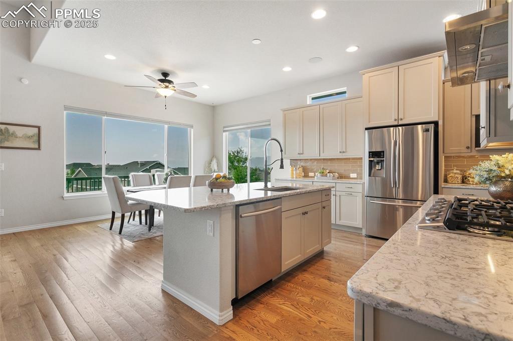 Kitchen featuring appliances with stainless steel finishes, ventilation hood, ceiling fan, backsplash, and recessed lighting