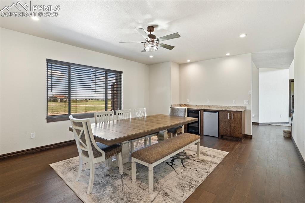 Dining space featuring beverage cooler, dark wood floors, a ceiling fan, bar area, and recessed lighting