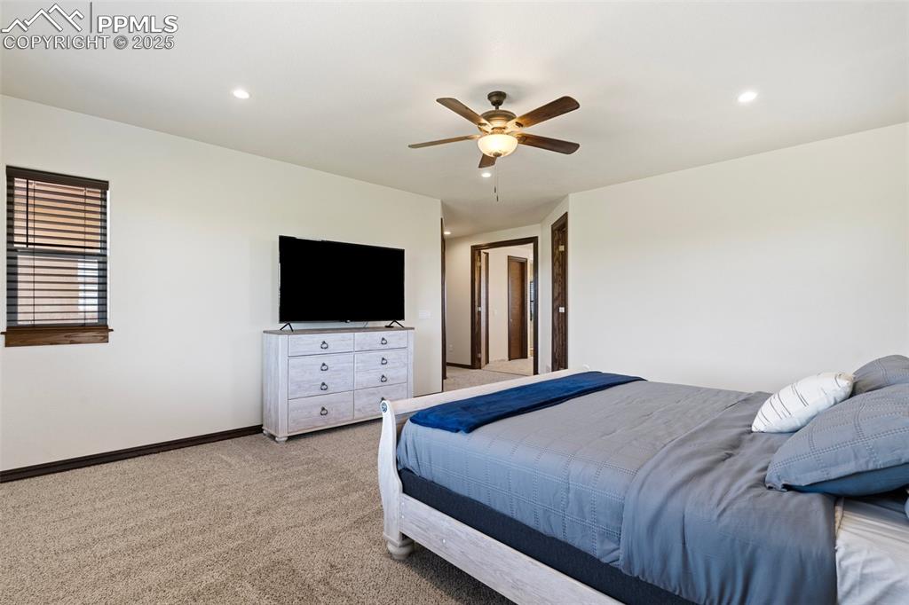 Main level Primary Bedroom featuring light colored carpet, a ceiling fan, and recessed lighting