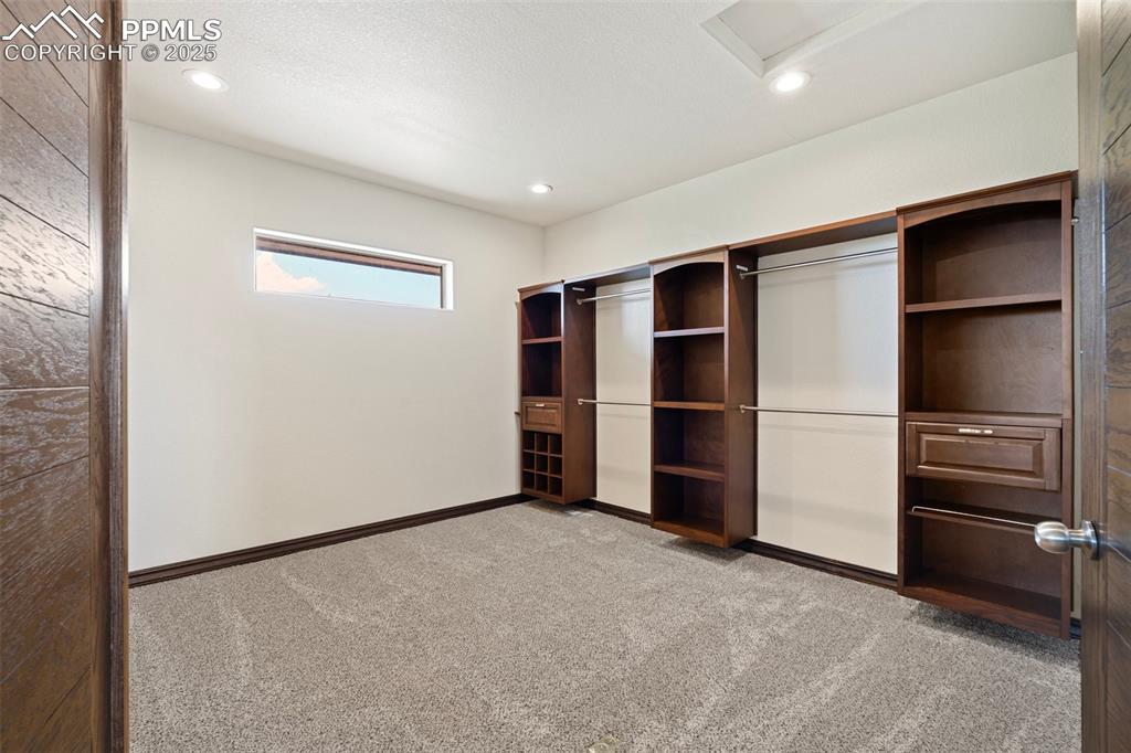 Second walk-in primary closet featuring carpet