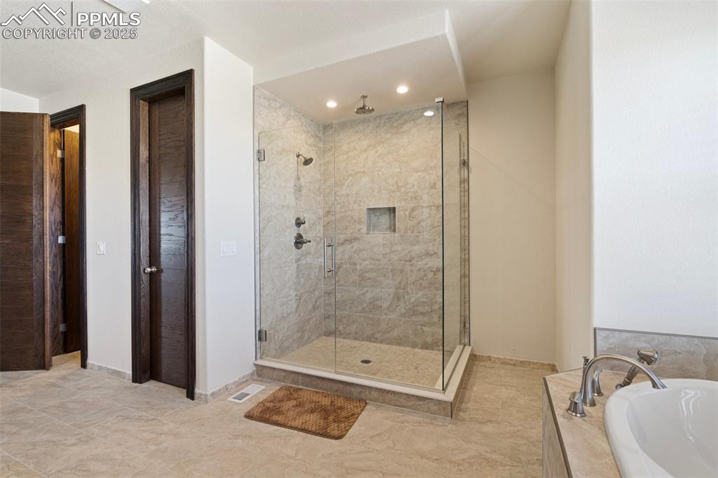 Main level Primary Bathroom featuring a stall shower, a bath, and recessed lighting