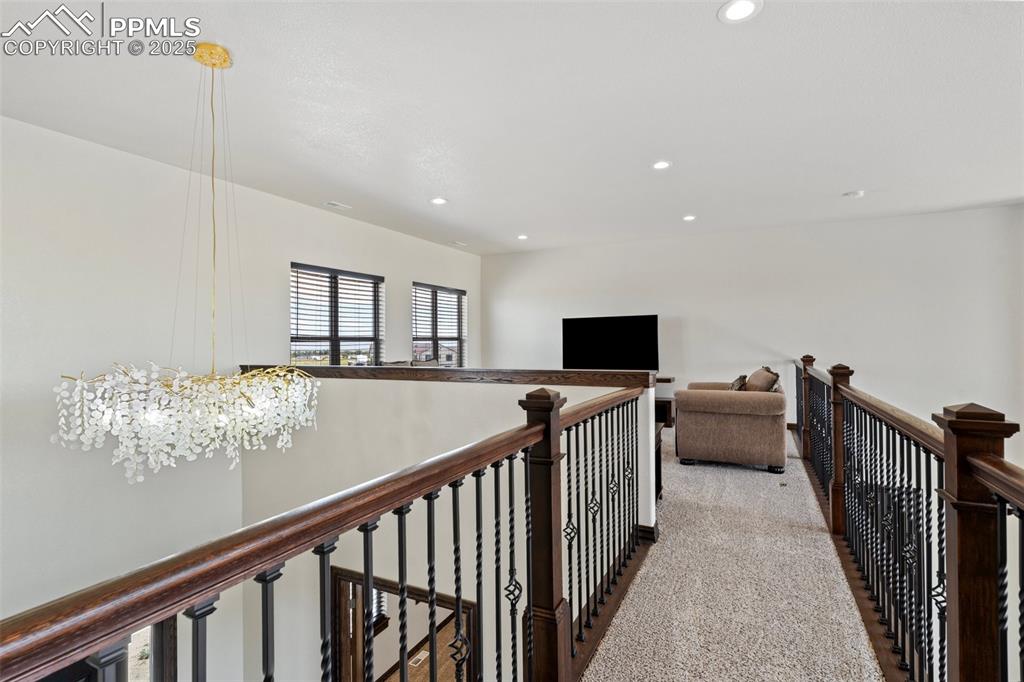 Corridor with recessed lighting, an upstairs landing, carpet flooring, and a chandelier