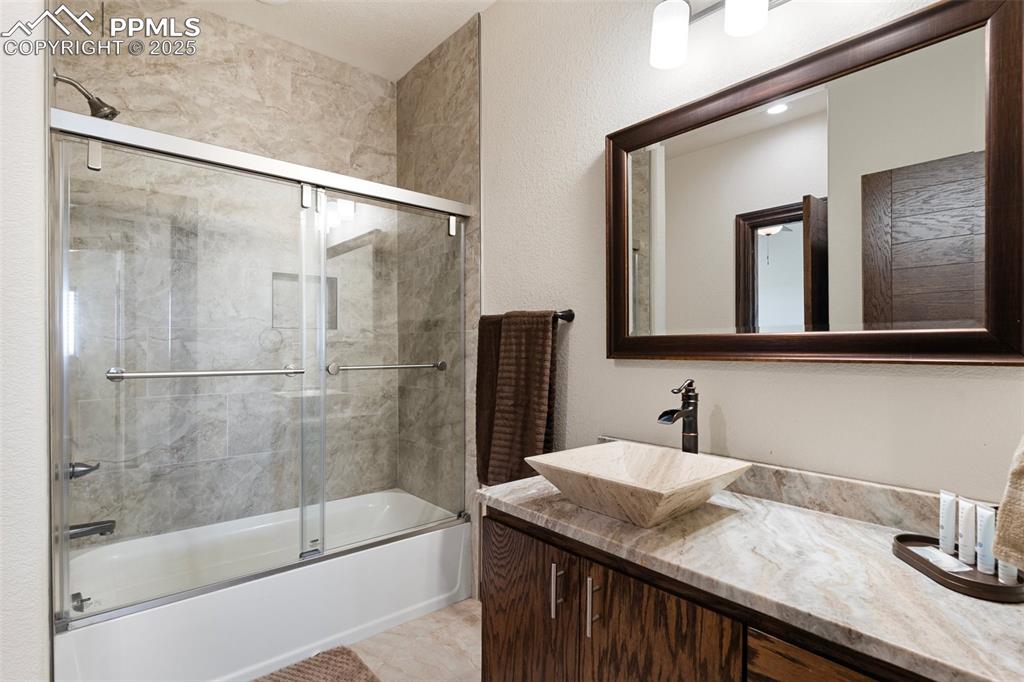 Bathroom with combined bath / shower with glass door and vanity