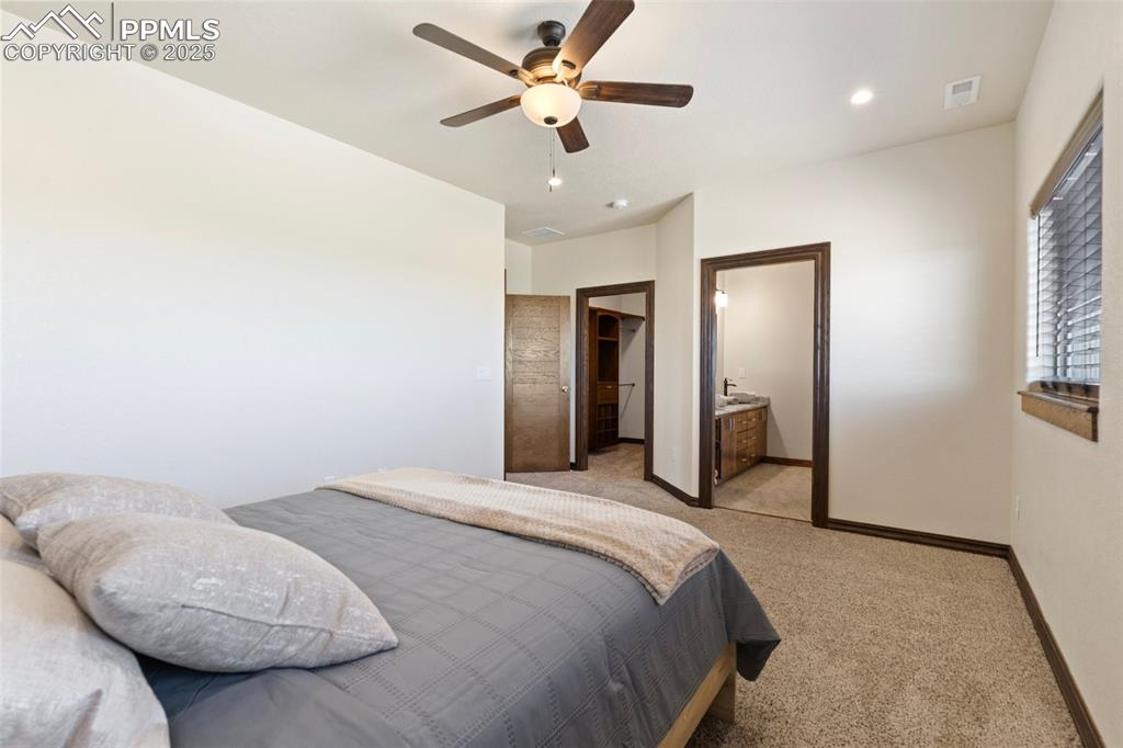 Bedroom featuring light carpet, a spacious closet, recessed lighting, a ceiling fan, and connected bathroom