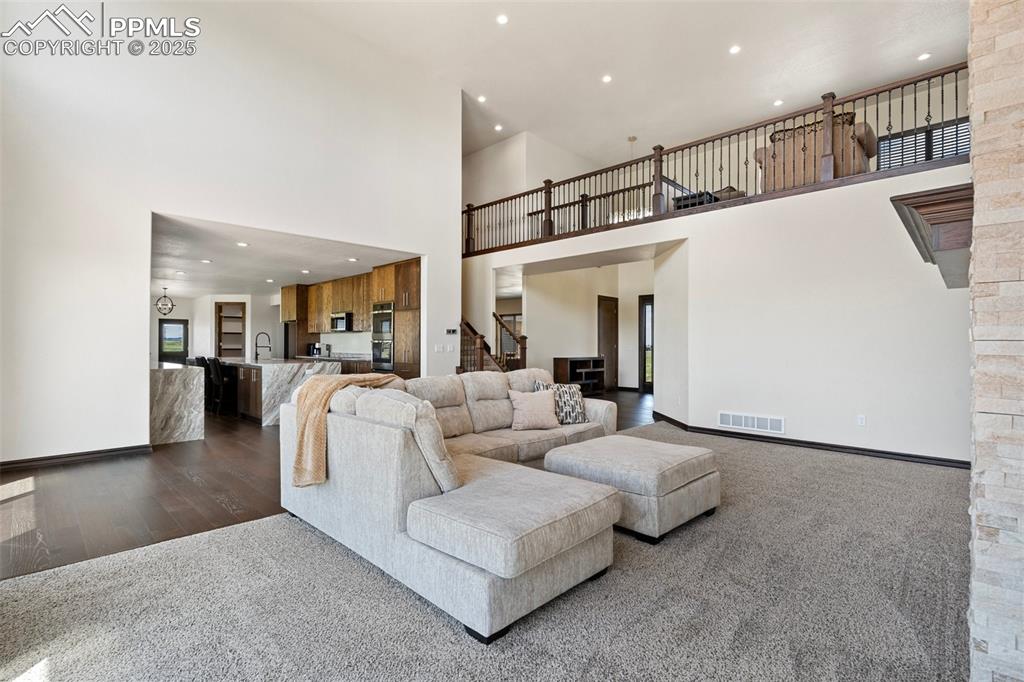 Living area with recessed lighting, stairway, a high ceiling, dark wood finished floors, and carpet