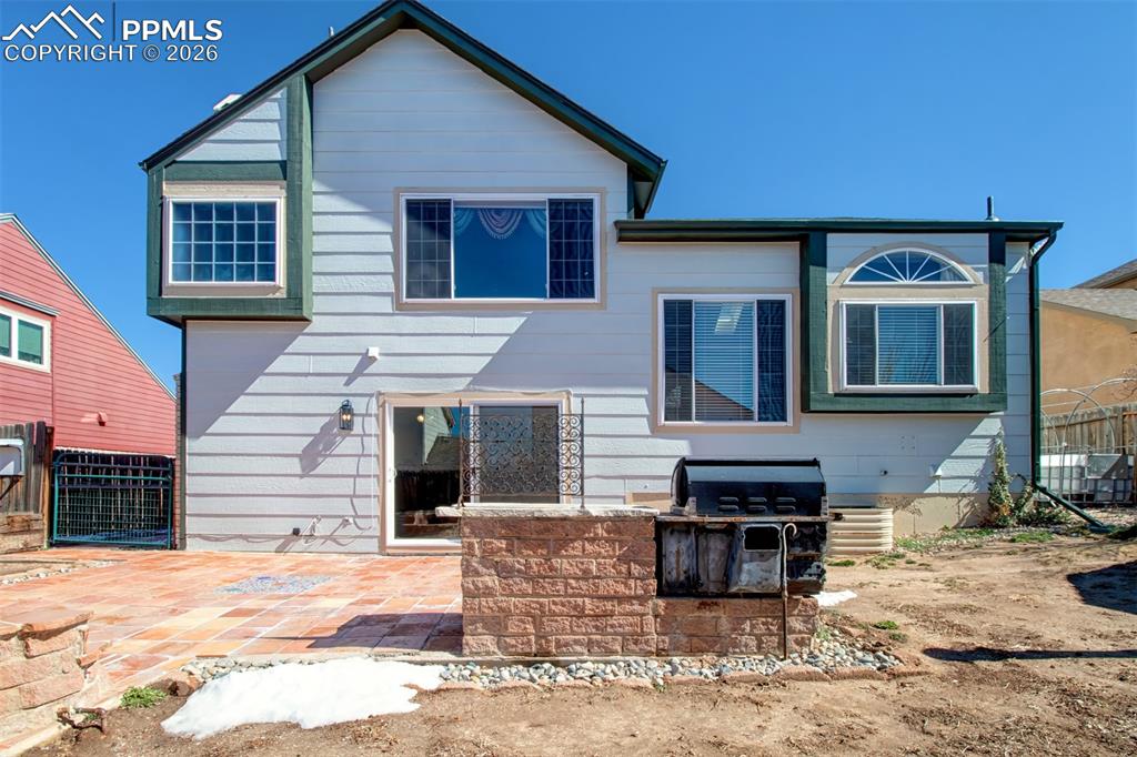 Tile patio, gas firepit (capped off), built-in grill, dog run to the left and garden beds to the right. 