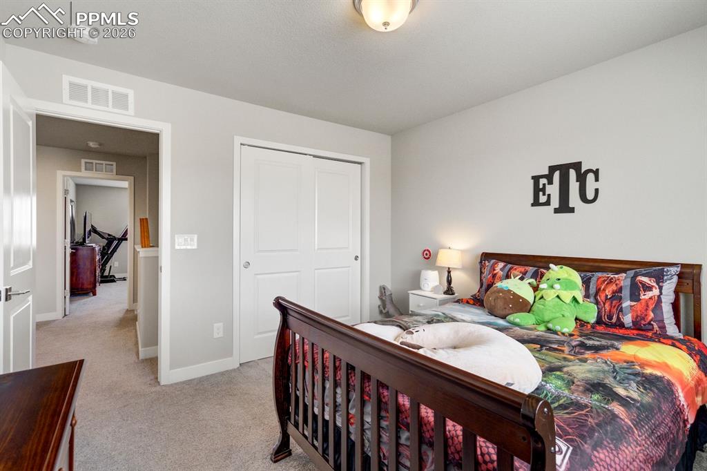 Bedroom with light colored carpet and a closet