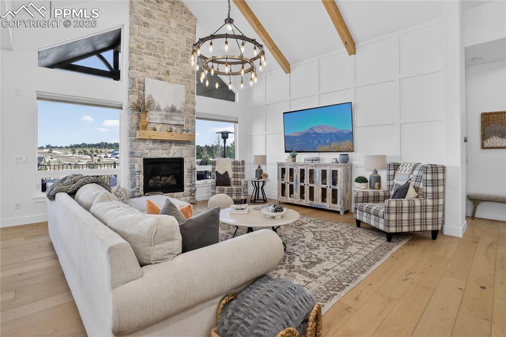 Great Room with vaulted ceilings, knotty alder wood beams, stone fireplace, and wide-plank wood floors