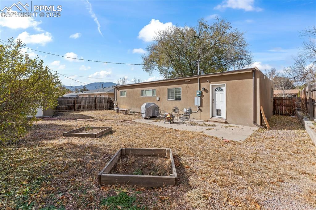 Back of house featuring a patio, a vegetable garden, stucco siding, and a fenced backyard