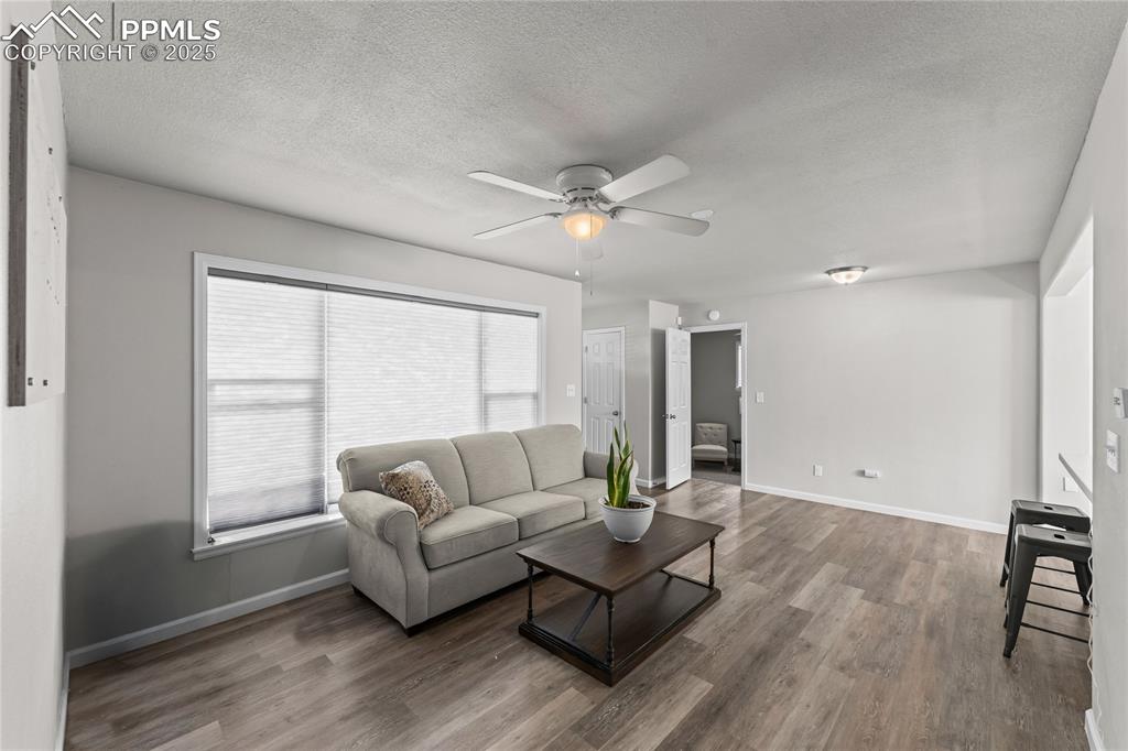 Living area with a textured ceiling, wood finished floors, and ceiling fan