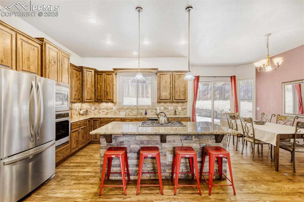 Kitchen with stainless steel appliances, a kitchen island, tiled backsplash, and a breakfast bar