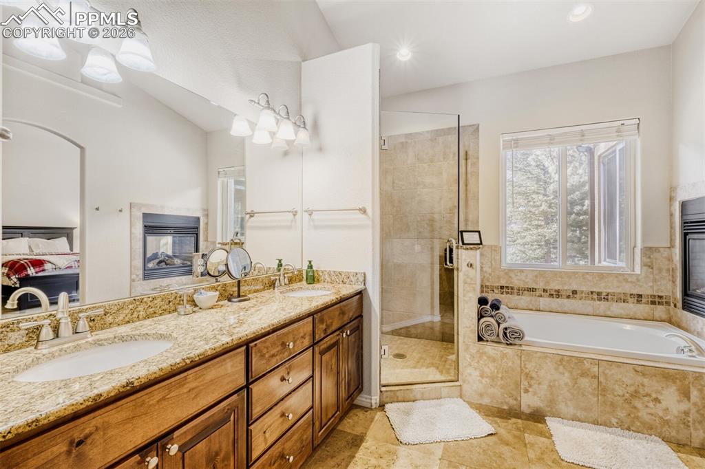 Ensuite bathroom with double vanity, a garden tub, a stall shower, and recessed lighting and fireplace