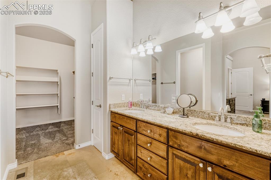5-piece bathroom with double vanity, a walk-in closet, and Travertine floors