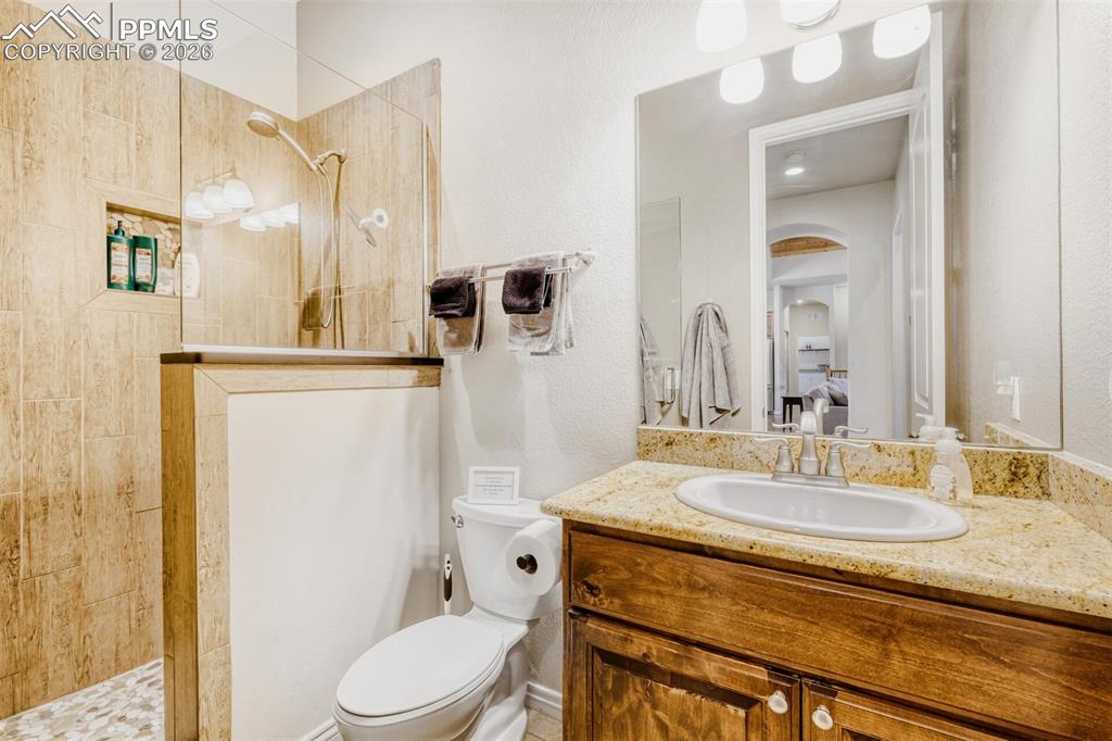 Main level three quarter bathroom with walk in shower, and granite vanity located next to the secondary bedroom