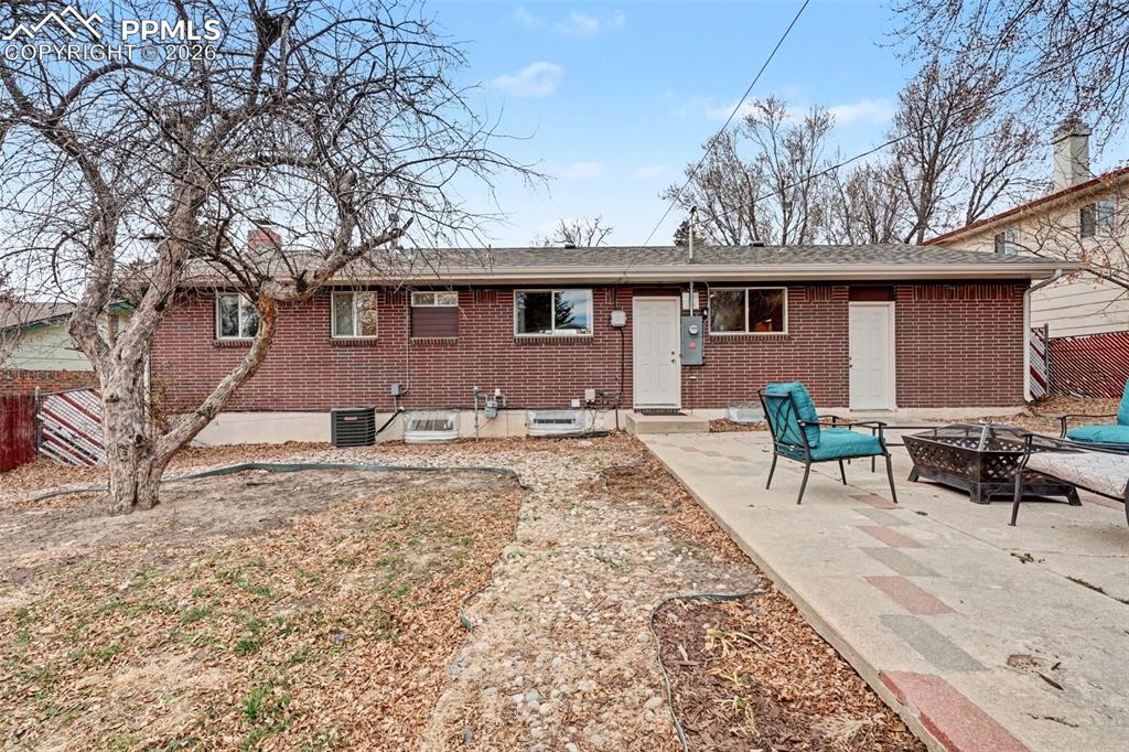 Back of property featuring a fire pit, brick siding, and a patio