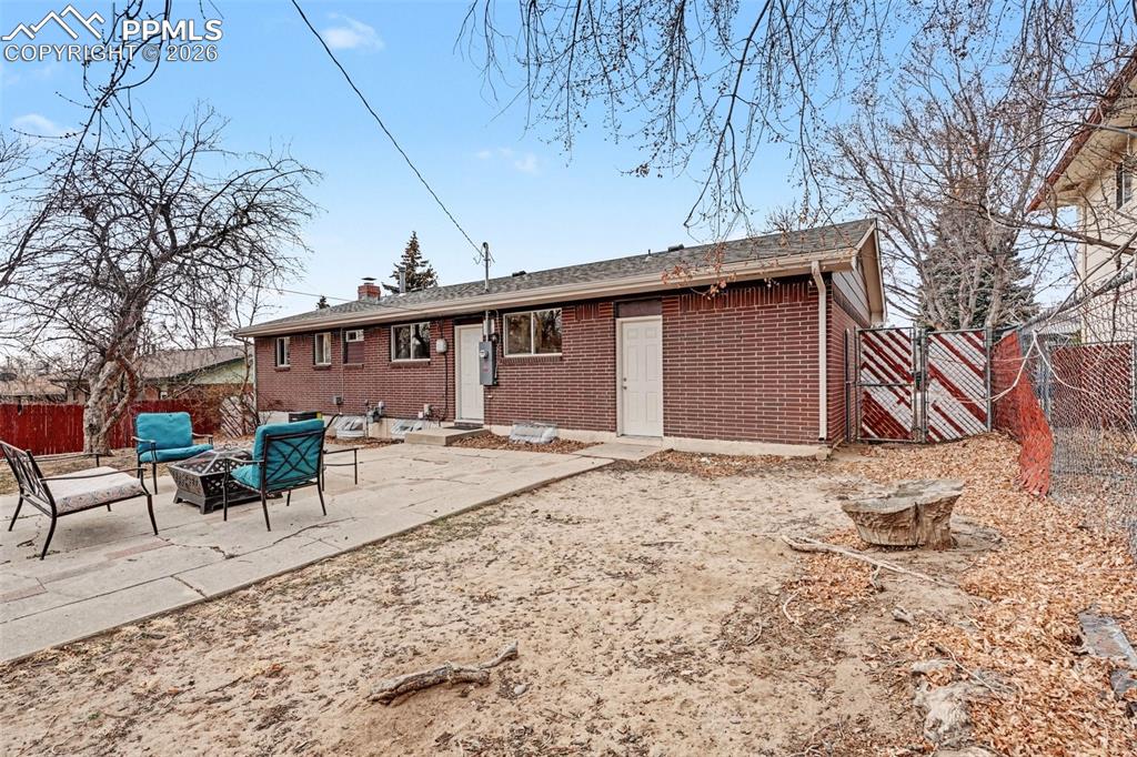 Back of house with a fire pit, brick siding, a patio area, and a chimney