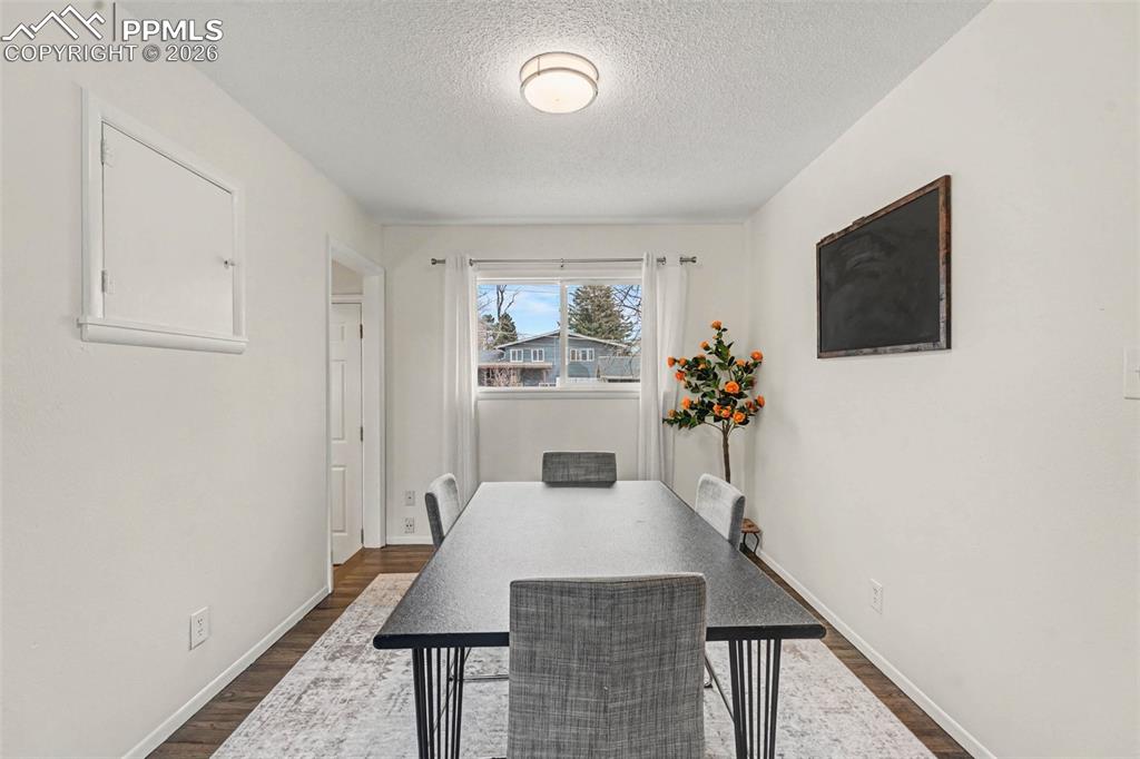 Dining area with a textured ceiling and dark wood-style flooring