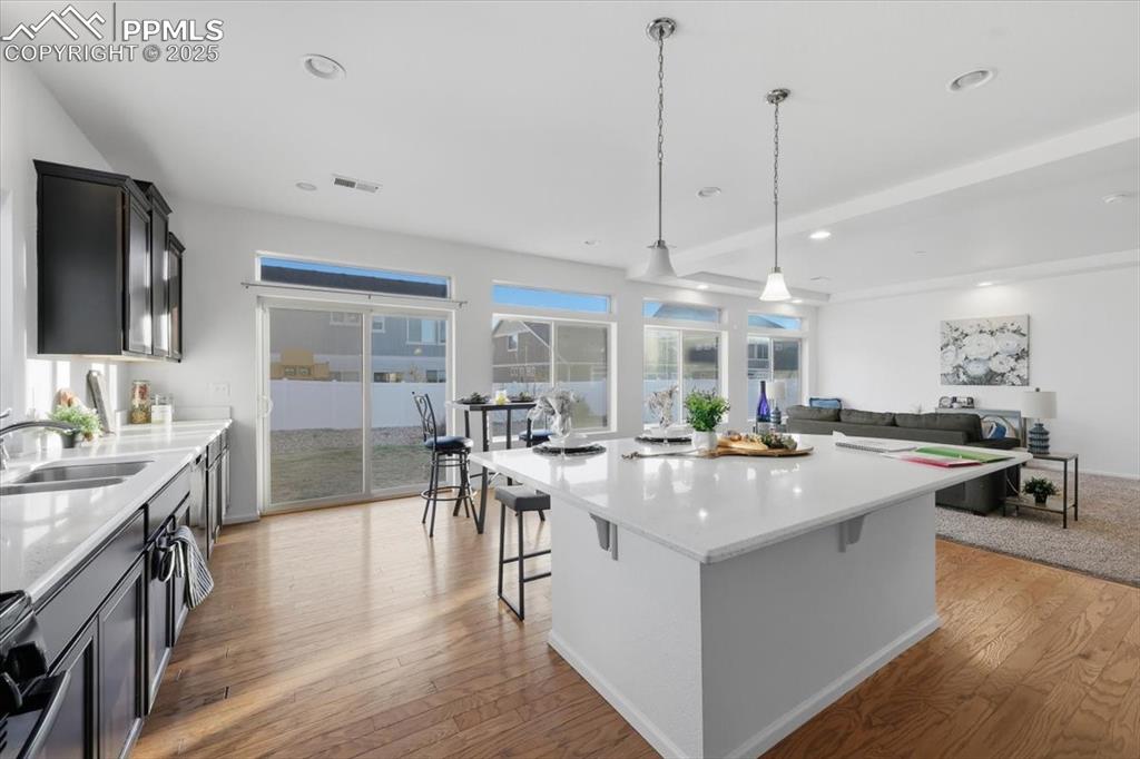 Kitchen with light stone counters, pendant lighting, open floor plan, light wood-style flooring, and recessed lighting