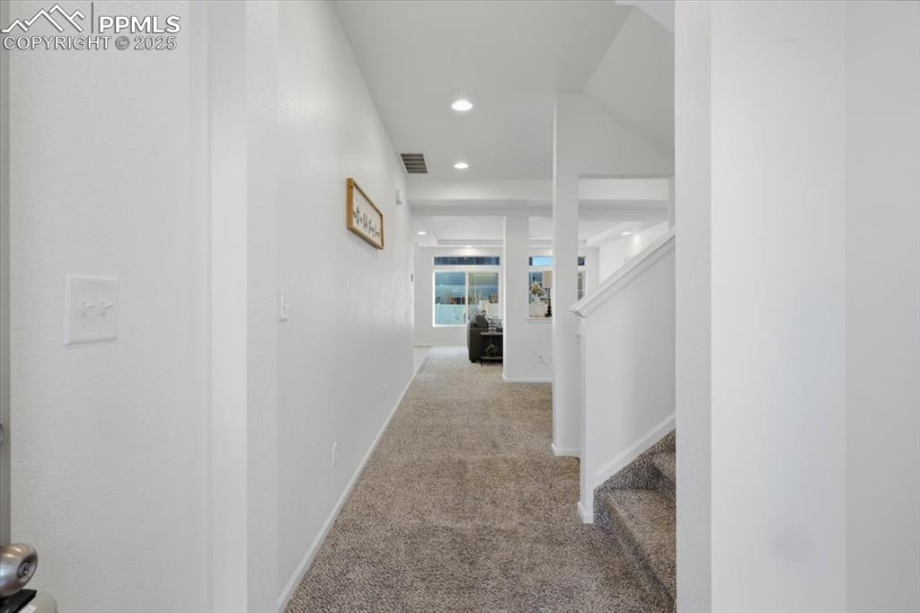 Corridor with carpet, stairs, and recessed lighting