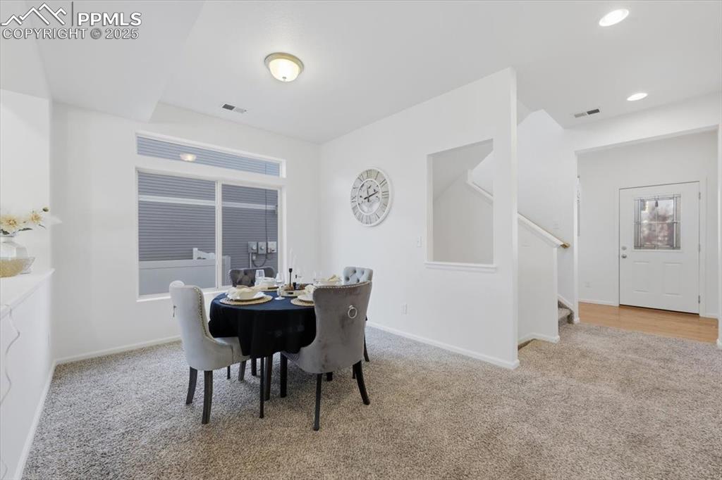 Dining space featuring light colored carpet, stairs, and recessed lighting