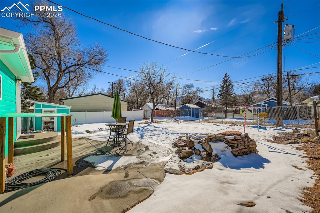 Large, fully fenced backyard with concrete patio, water feature, and alley access.