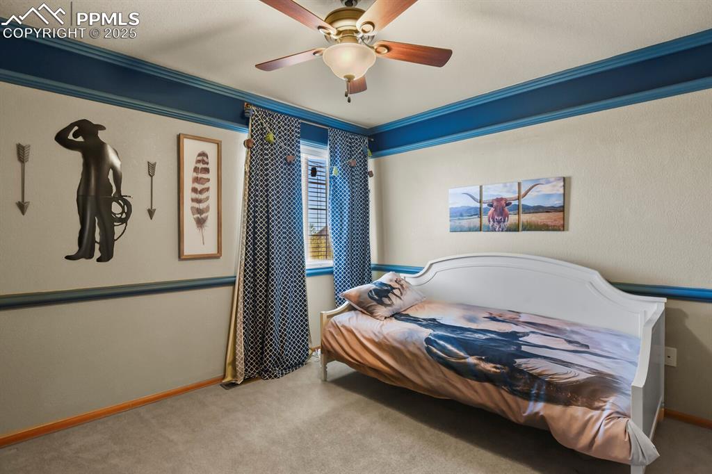 Carpeted bedroom featuring ornamental molding and a ceiling fan