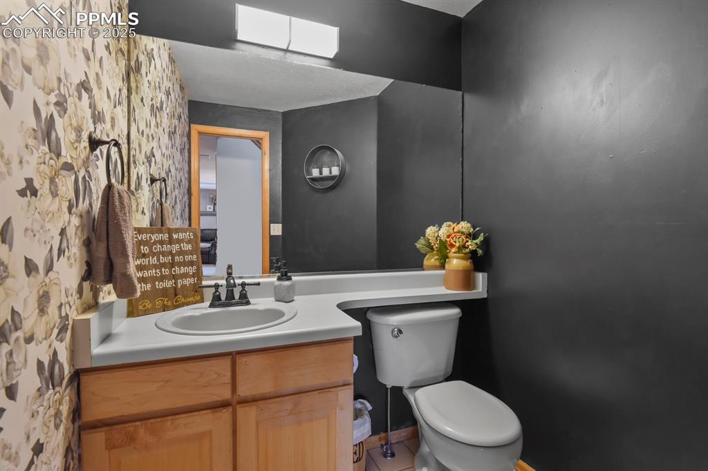 Half bathroom with vanity, wallpapered walls, a skylight, and tile patterned floors