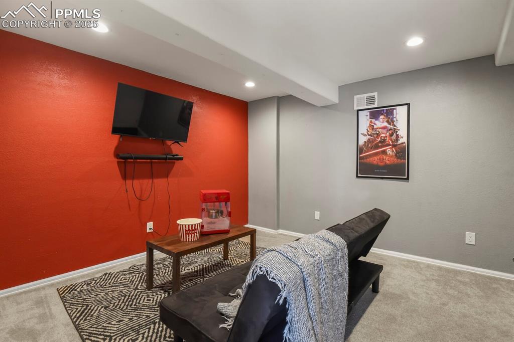 Living area with light carpet, recessed lighting, and a textured wall