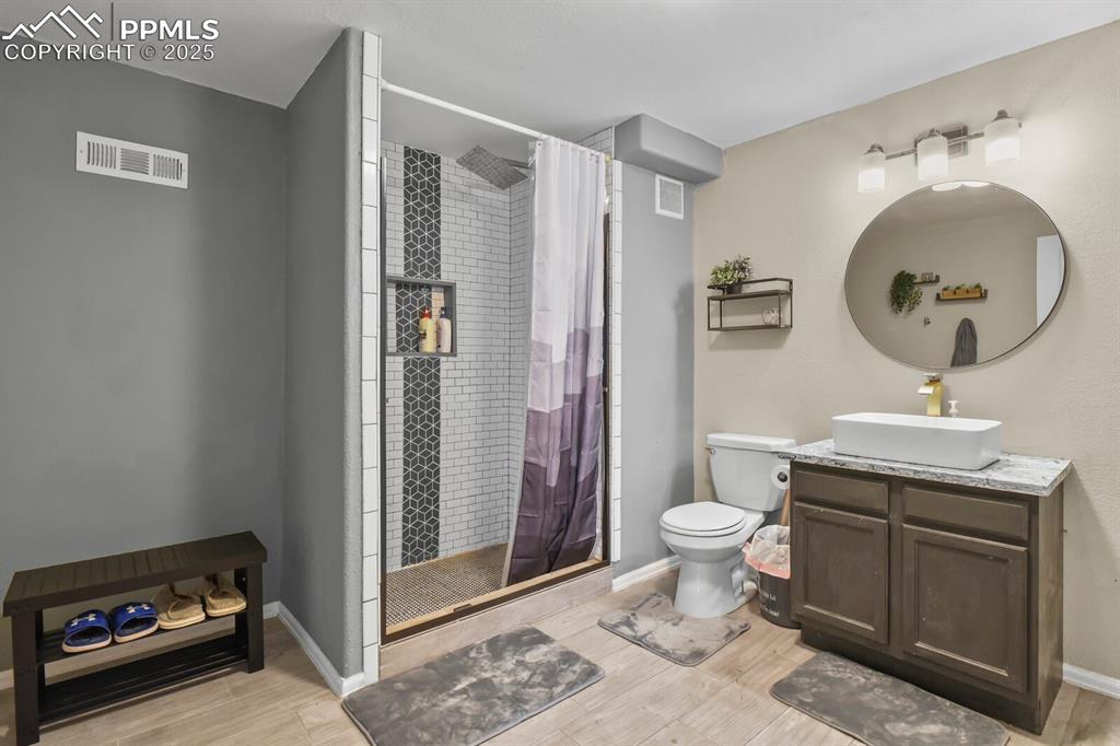 Full bathroom with vanity, a shower stall, and light wood-style floors