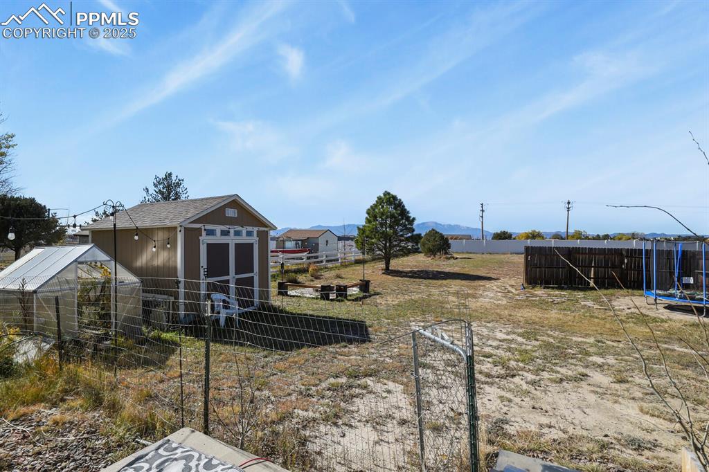 View of yard featuring a trampoline and a storage shed