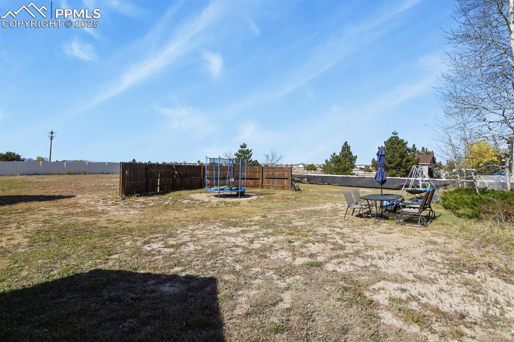 Fenced backyard with a trampoline and outdoor dining area