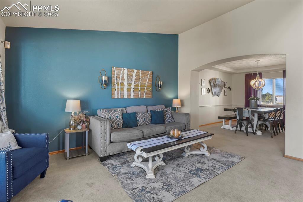 Living room with arched walkways, carpet, and a chandelier