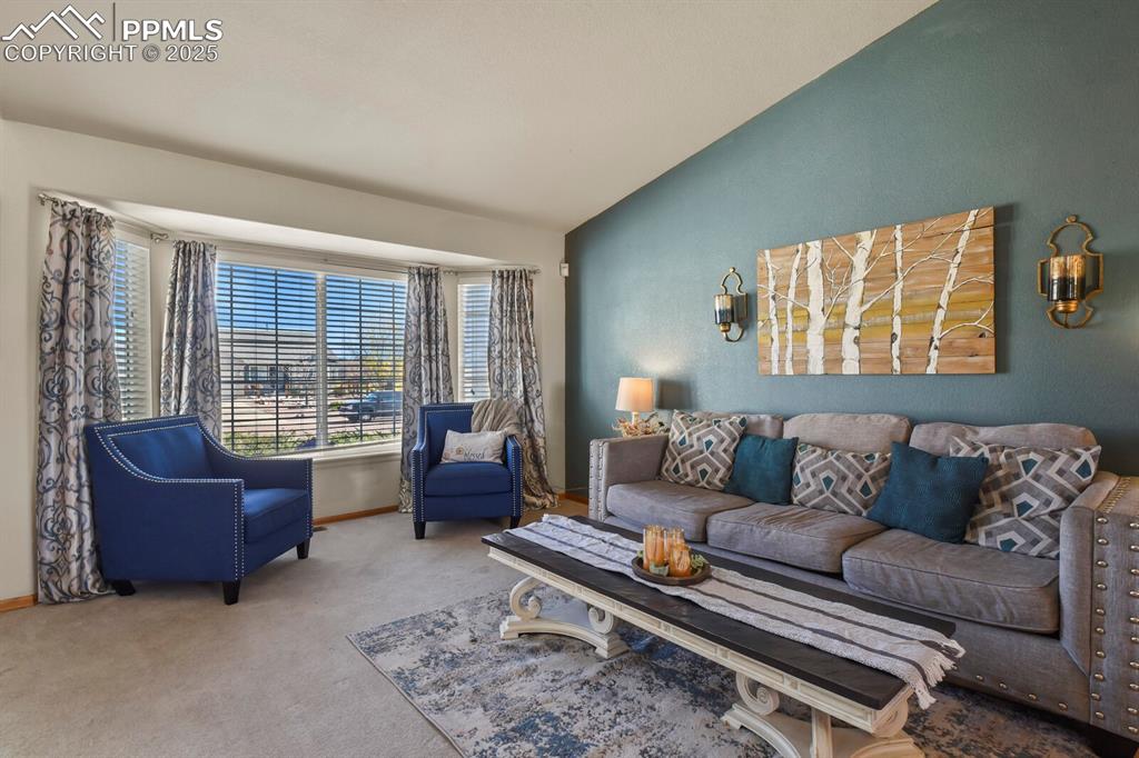 Carpeted living room with vaulted ceiling and baseboards