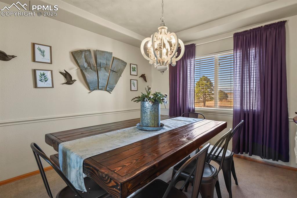 Dining area with light carpet and a chandelier