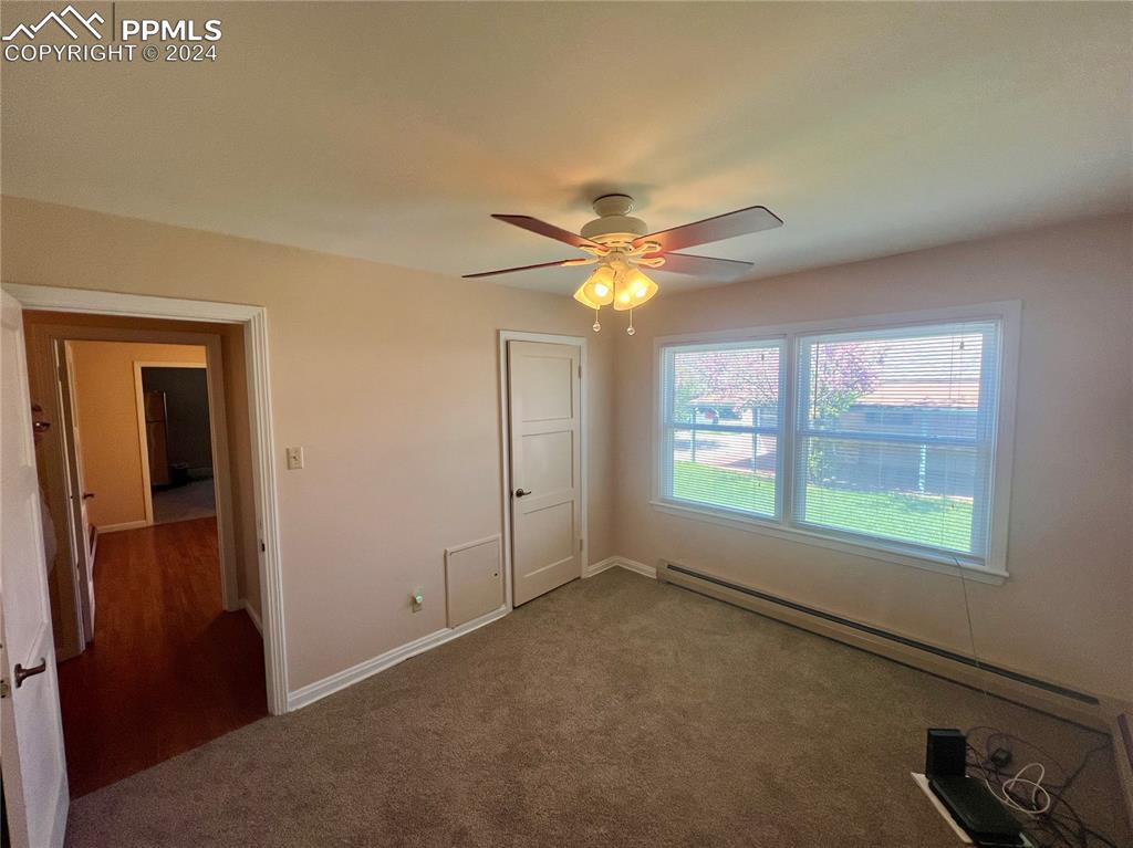 Unfurnished bedroom with hardwood / wood-style floors, ceiling fan, and baseboard heating