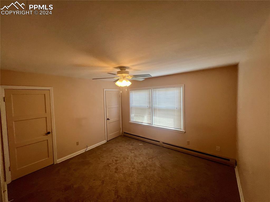 Carpeted spare room with a baseboard heating unit and ceiling fan