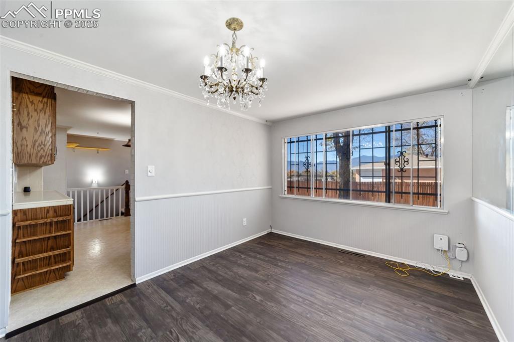 Unfurnished room featuring crown molding, dark wood-style flooring, and a chandelier