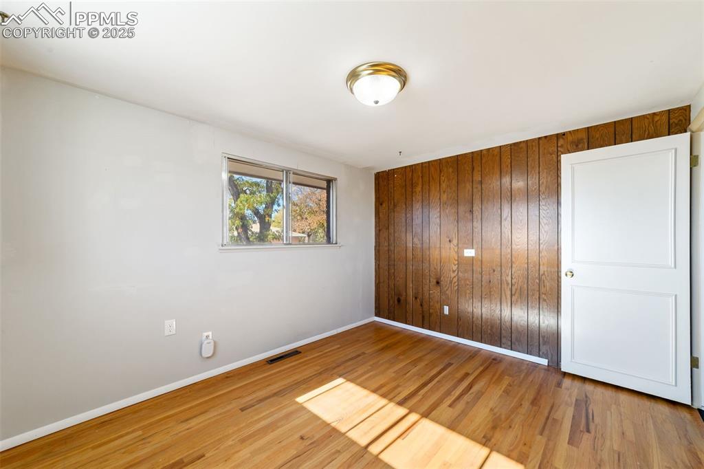 Spare room with wood walls and light wood-style flooring