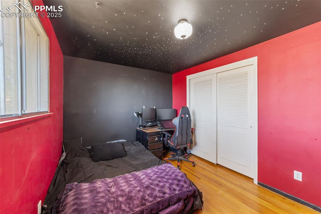 Bedroom featuring light wood-type flooring, an office area, and a closet