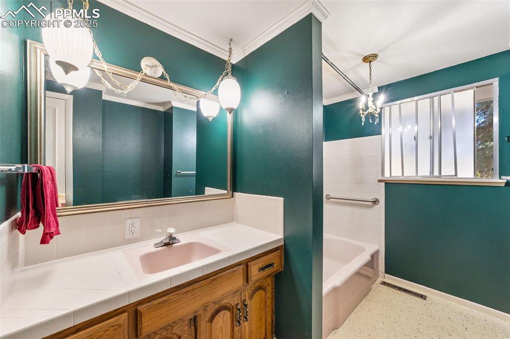 Bathroom with vanity, ornamental molding, shower / tub combination, and speckled floor