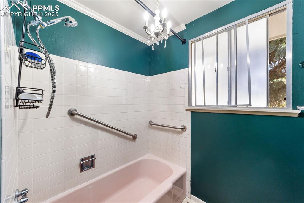 Full bath with  shower combination, ornamental molding, and a chandelier