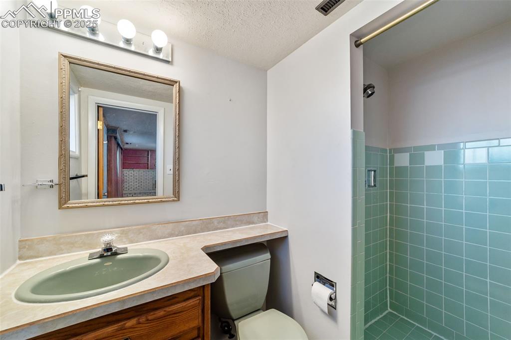Bathroom with a stall shower, vanity, and a textured ceiling