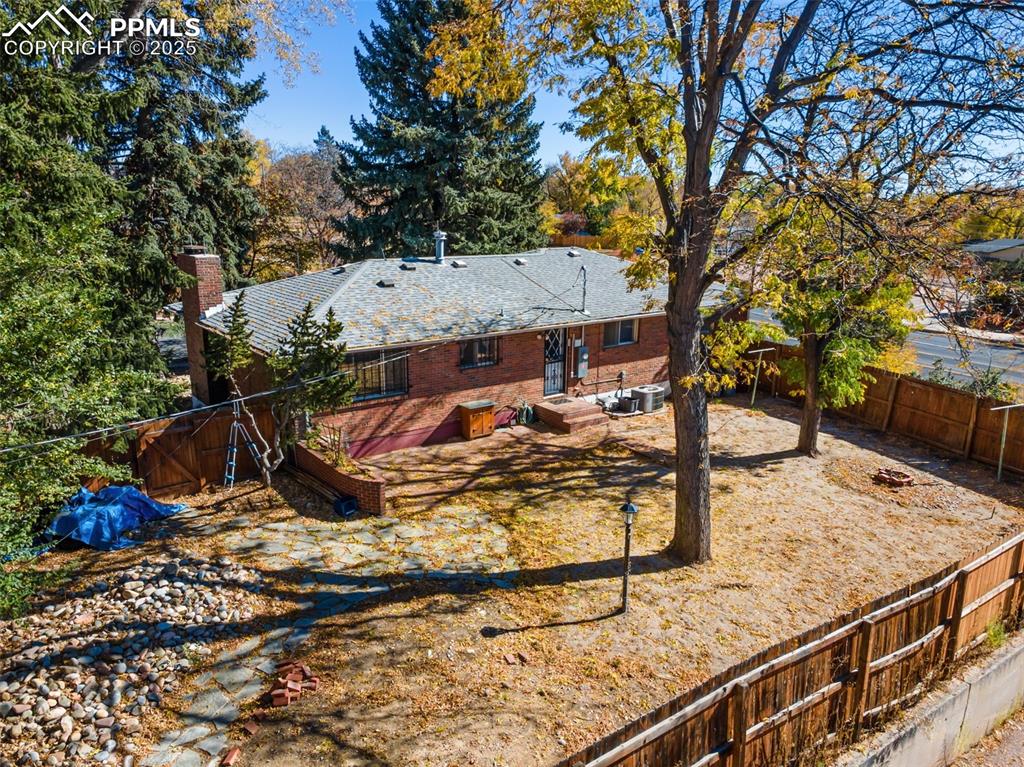 Rear view of property with a fenced backyard, a chimney, and brick siding