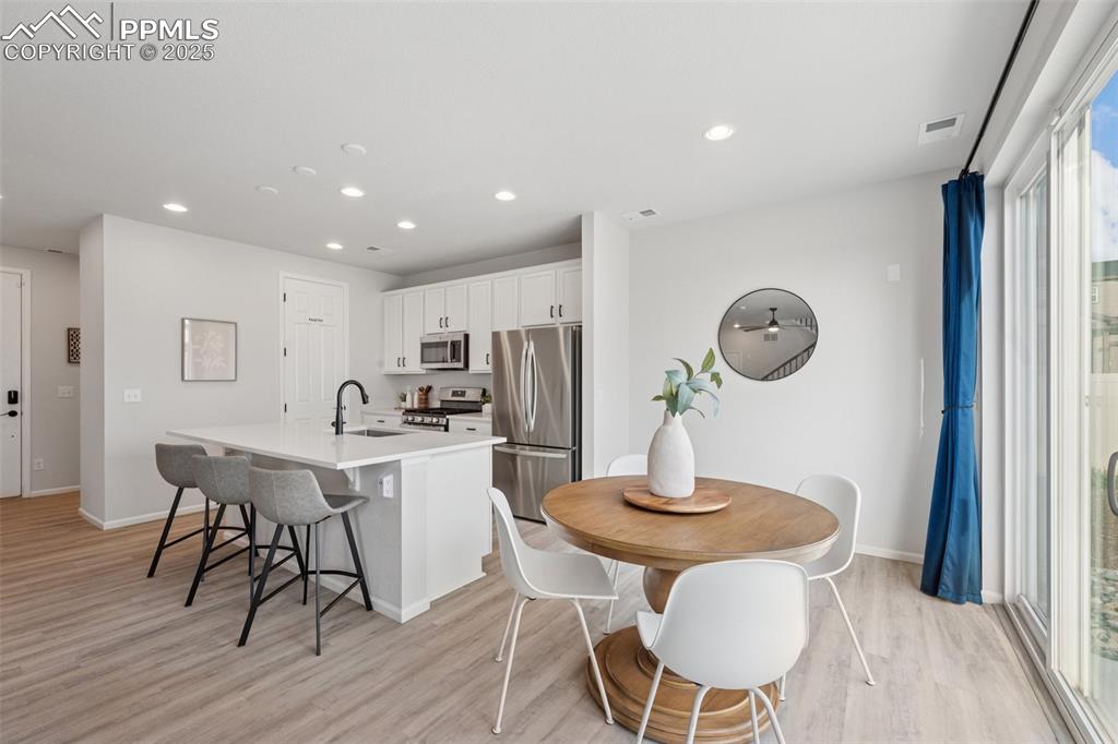 Kitchen featuring a kitchen island with sink, light wood-style floors, appliances with stainless steel finishes, recessed lighting, and white cabinetry
